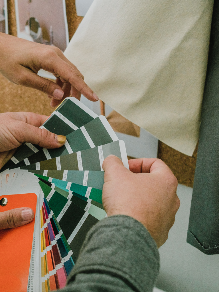 Hands holding paint swatches and comparing it with fabric to illustrate the basement design process for our basement remodeling projects