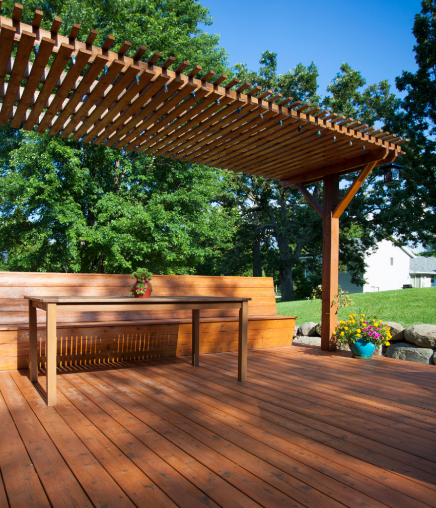 Example of a beautiful deck building project made with rich cedar wood and featuring built-in bench seat with a large shade-giving pergola