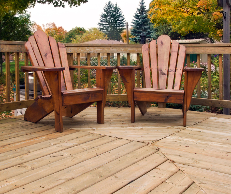 A natural wood deck with two adirondack chairs