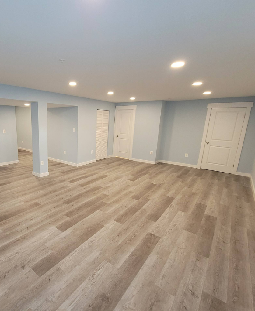 A basement featuring beautiful wide-paneled engineered wood flooring installed by The Homeowners Helper