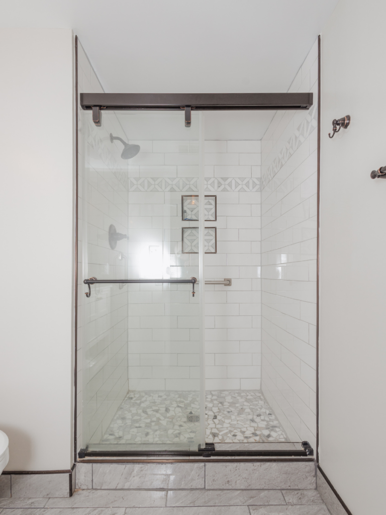 A shower with glass door, tile walls, and tile flooring from one of our recent bathroom remodeling projects