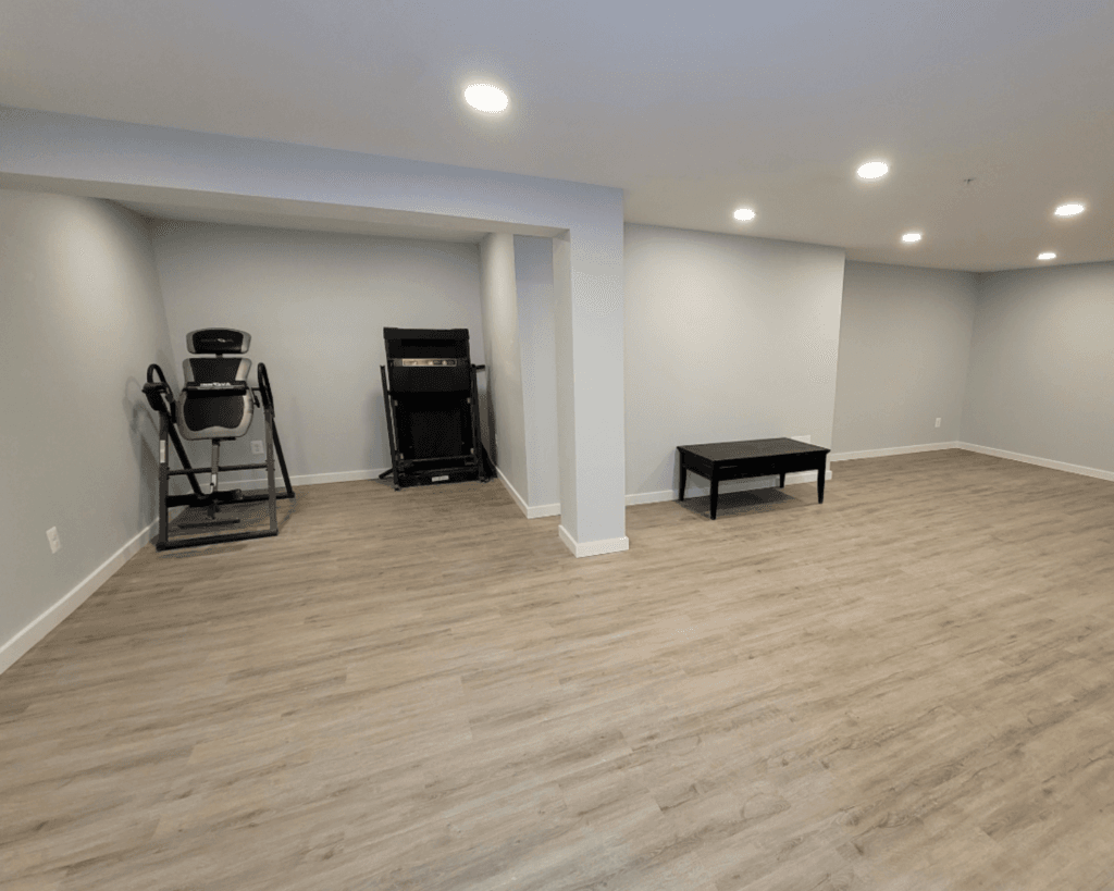 A basement remodel project with light blue walls and soft gray hardwood floors.