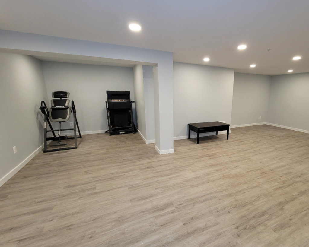 A basement remodel project with light blue walls and soft gray hardwood floors.