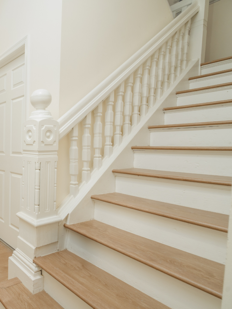 A restored staircase with oak wood flooring in a historic home from a flooring project by the homeowners helper