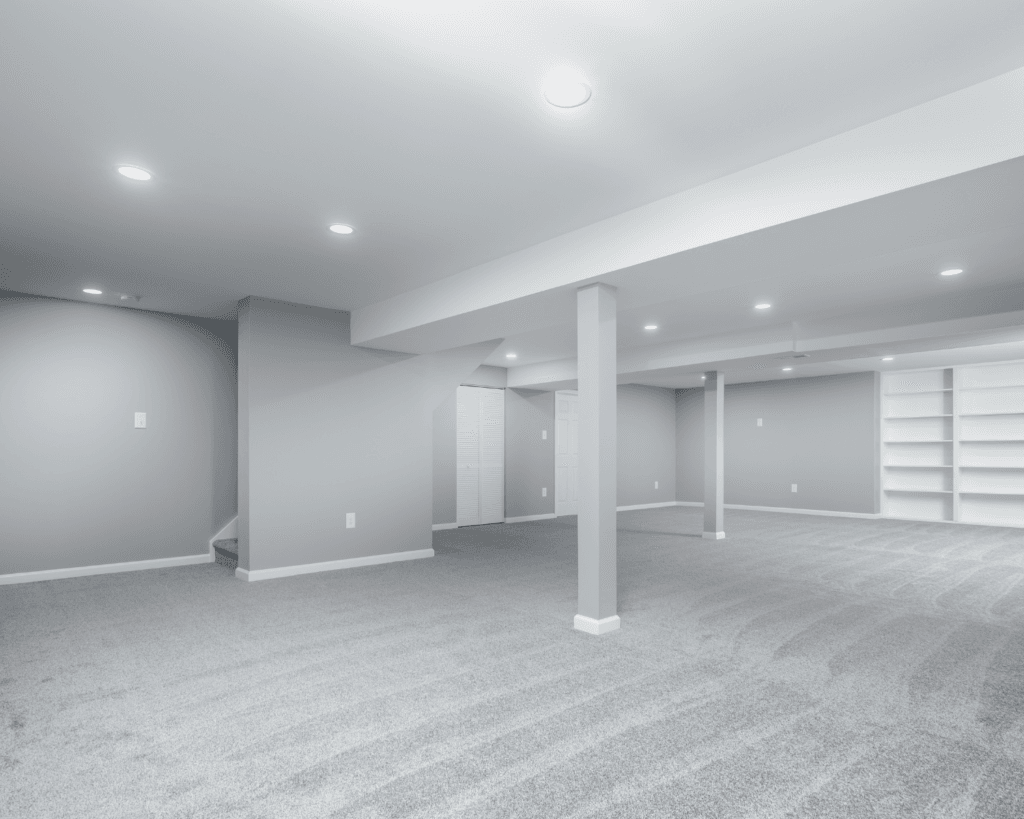 A basement remodel by The Homeowners Helper LLC with wall to wall grey carpeting and custom built in shelving.