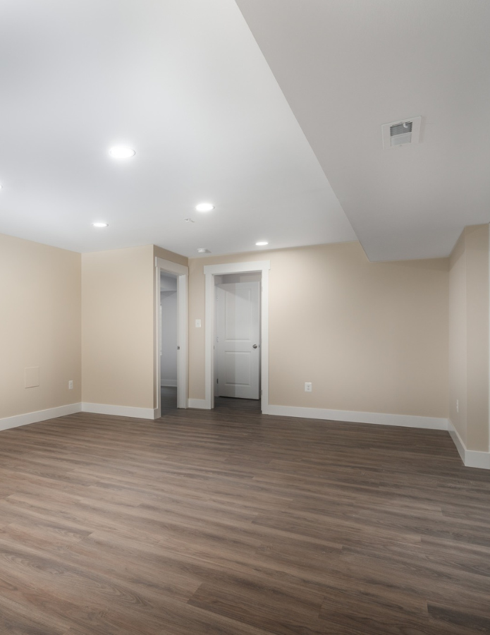 A remodeled basement with neutral cream walls and beautiful engineered hardwood flooring
